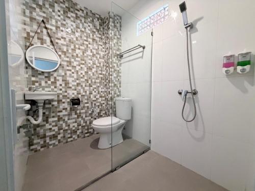 a bathroom with a shower with a toilet and a sink at Pondok DenAyu Homestay in Kuta