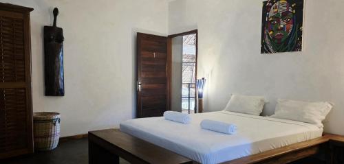 a bedroom with a white bed with two pillows on it at Maison Carrée Andilana in Andilana