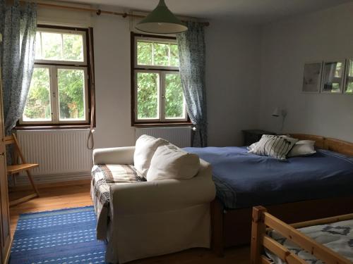 a bedroom with a bed and a couch and windows at Alte Schule Nausdorf in Lenzen