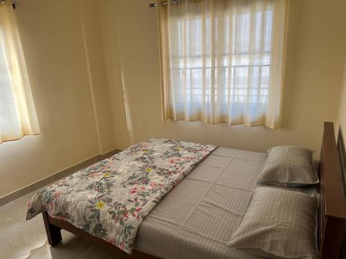 a bedroom with a bed with a flowered blanket on it at Chippy Residency Coorg in Gonikoppal