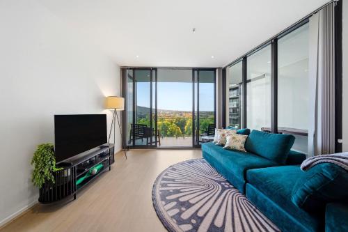 a living room with a blue couch and a flat screen tv at Stylish 1-Bed in CBD with Secure Underground Parking in Canberra