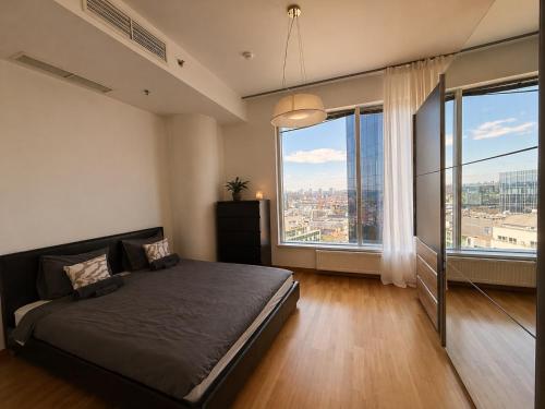 a bedroom with a bed and two large windows at Panoramic Sea View - 12th floor in Tallinn