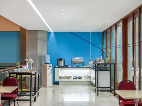 a kitchen with blue walls and tables and chairs at Ibis Budget Jakarta Menteng in Jakarta