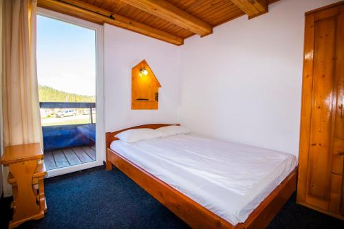 a bedroom with a bed and a large window at Pensiunea HEIDI in Vartop