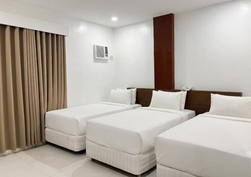 a hotel room with two beds and a couch at Cris Inn - Bayugan in Bayugan City