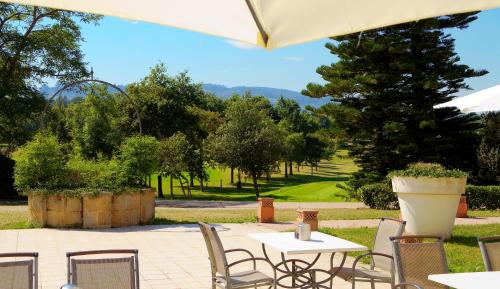 a patio with a table and chairs and trees at Oca Palacio De La Llorea Hotel & Spa in Deva