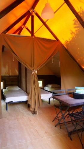 a tent with two beds and a table in it at Camping Canal de Berry in Saint-Amand-Montrond