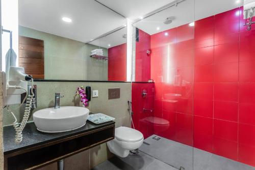 a red bathroom with a toilet and a sink at SinQ Prive in Candolim