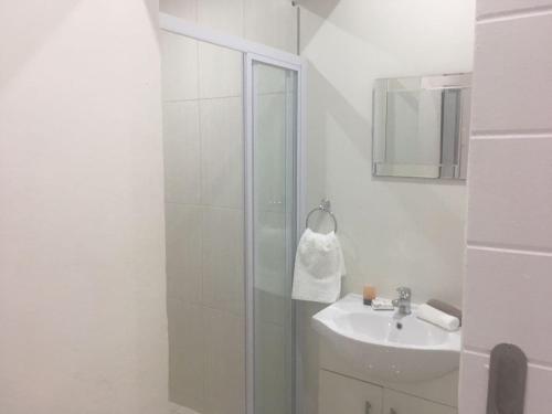 a white bathroom with a shower and a sink at Paarl Mountain Lodge in Paarl