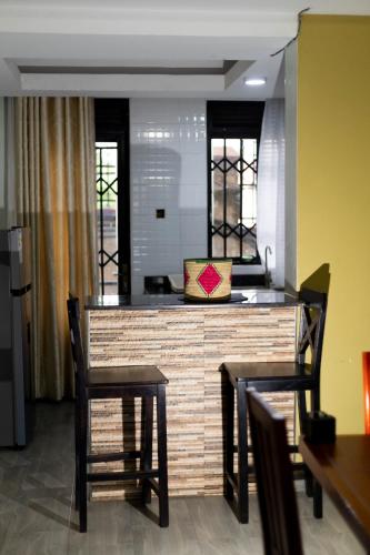 a kitchen with a bar with two chairs and a table at NL Josephine's Hotel, Apartment in Kampala