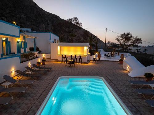 a swimming pool in the middle of a patio with a table and chairs at Ancient Thera Apartments in Kamari