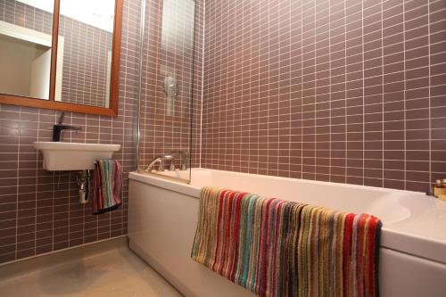 a bathroom with a tub and a sink and a mirror at Park Row Apartments in Leeds