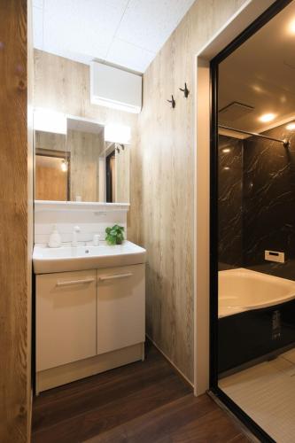 a bathroom with a sink and a tub next to a mirror at KiyosuBase2 in Kiyosu