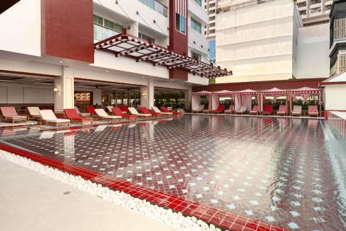 an empty swimming pool in a building with red chairs at Blue Cabin Hotel Formerly A-ONE New Wing Hotel in Pattaya