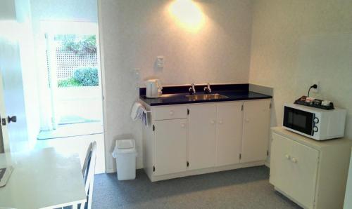 a kitchen with a sink and a microwave at Riverview Motel in Whanganui