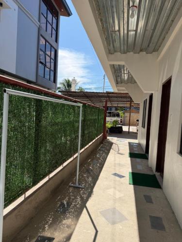 a building with a green hedge next to a fence at Anda Seabreeze Pension Haus in Anda