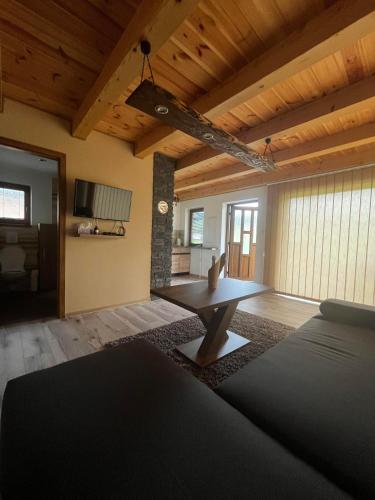 a living room with a wooden ceiling and a table at Chatka pod Stinskou in Zboj