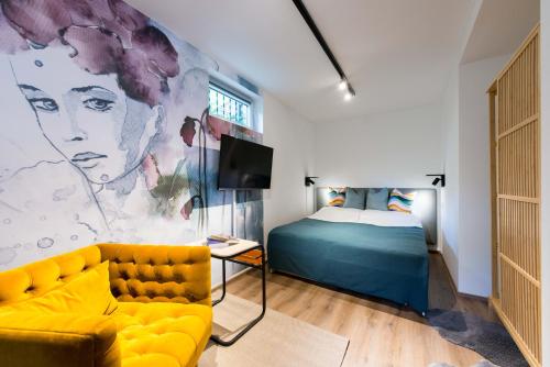 a bedroom with a bed and a yellow couch at CHICLIVING Appartements in St. Wolfgang