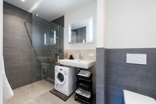 a bathroom with a sink and a washing machine at CHICLIVING Appartements in St. Wolfgang