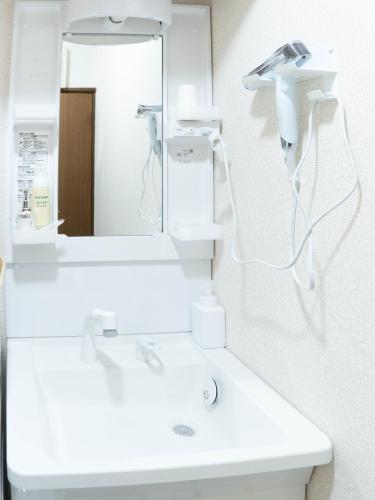 a bathroom with a white sink and a mirror at Coucou! in Takasaki