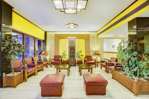 een wachtkamer met stoelen, tafels en planten bij Hotel Ajanta Continental in Dehradun