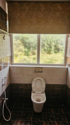 a bathroom with a toilet with a window at SPKA Jungle Resort in Vālpārai