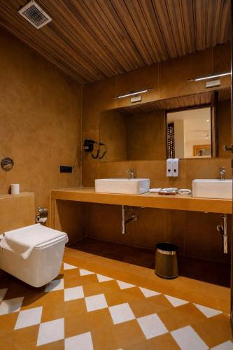 a bathroom with two sinks and a toilet and a mirror at Hotel Aurea Jaisalmer in Jaisalmer