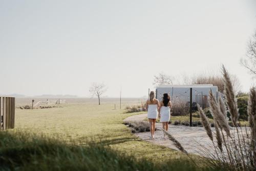 two women walking down a path in a field at Boutique Hotel Texel in De Cocksdorp