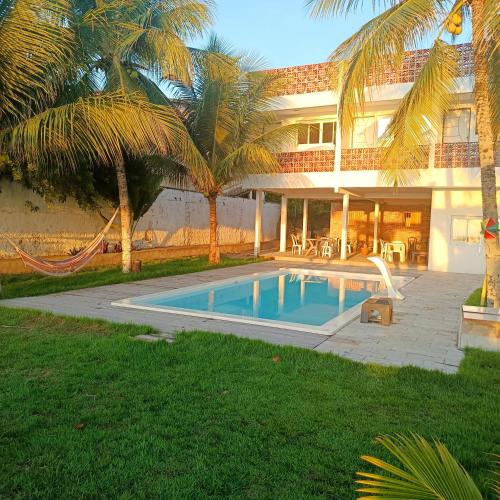 a house with a swimming pool in front of a house at Suites Dupla beira mar Carapibus in Conde