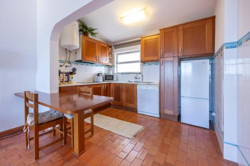 a kitchen with wooden cabinets and a wooden table at incredible view- T1 Salema in Salema