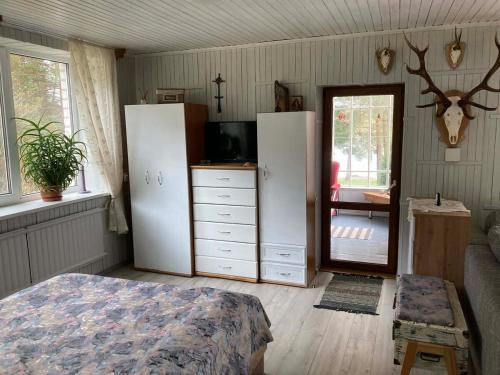 a bedroom with white cabinets and a bed and a mirror at Našio Kempingo Apartamentai in Antanaše