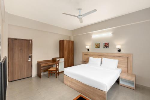 a bedroom with a white bed and a desk at Hotel Imphal by the Classic in Imphal