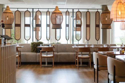 a restaurant with a couch and tables and chairs at Boutique Hotel Texel in De Cocksdorp