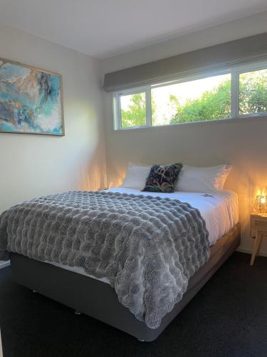 a large bed in a bedroom with two windows at Gold Star Haven in Napier
