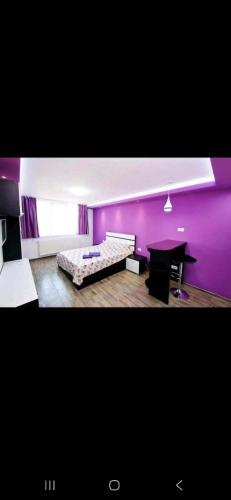 a purple room with a bed and a table at Tiglina in Galaţi