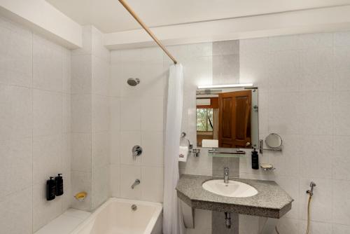 a white bathroom with a sink and a bath tub at The Classic Hotel in Imphal