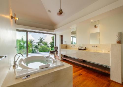 a large bathroom with a tub and a large window at Baan Asan in Taling Ngam Beach