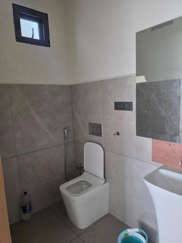 a bathroom with a toilet and a sink and a window at Amrutiya Farm in Bhuj