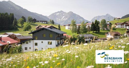 a village on a hill with a field of flowers at Lichterberg - Sommer-Bergbahnticket inklusive in Hirschegg