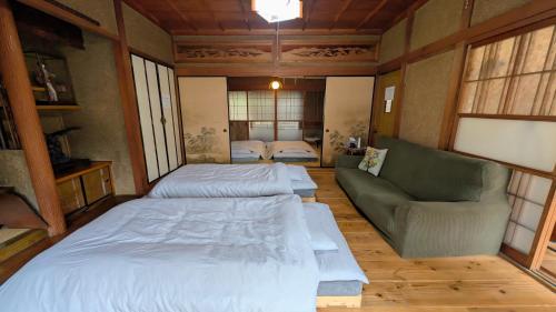two beds and a couch in a room with windows at Kominka engawa in Kakamigahara