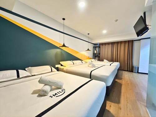 a room with three beds and a flat screen tv at Seeds Hotel Selayang in Batu Caves
