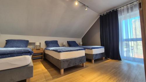 a bedroom with three beds and a window at Apartamenty Intermo Górna 7 in Świętochłowice