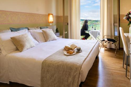 a large white bed with a plate of food on it at Hotel La Fonte in Osimo