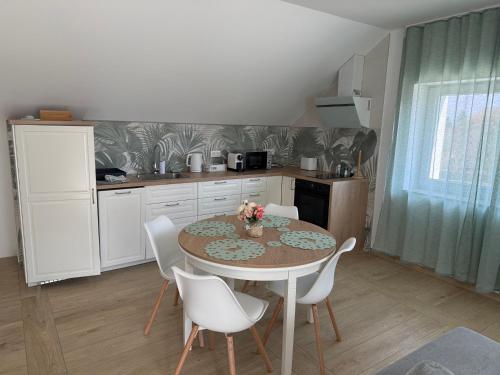 a kitchen with a table and white chairs and a table and a kitchen at Völgyzugoly Apartman in Kőszeg