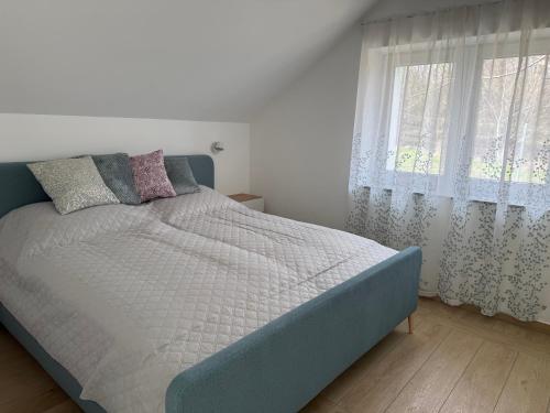 a bed in a white bedroom with a window at Völgyzugoly Apartman in Kőszeg