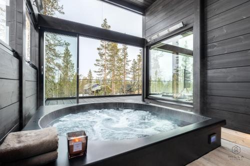 a jacuzzi tub in a room with large windows at ConstaVilla by Hilla Villas in Kolari