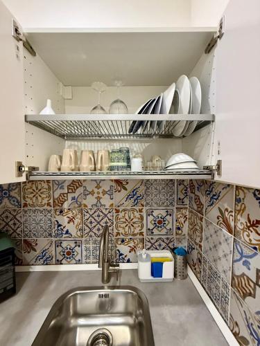 a kitchen with a sink and tiles on the wall at Ballaro's Vibe Historical Apartment Cathedral District in Palermo