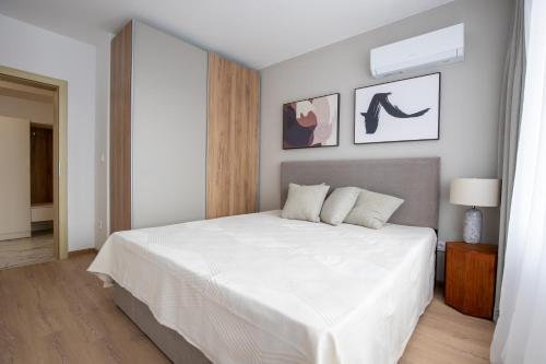 a white bedroom with a large bed with white sheets at SoleMare One-Bedroom Apartment in Burgas