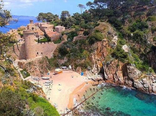 a group of people on a beach next to a castle at Pensión Jordi Tossa de Mar in Tossa de Mar