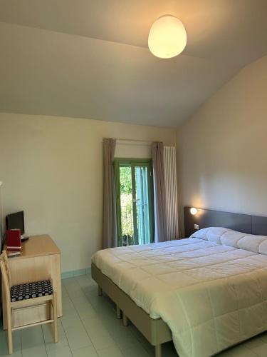 a bedroom with a bed and a desk and a window at Locanda La Cavallina in Brisighella